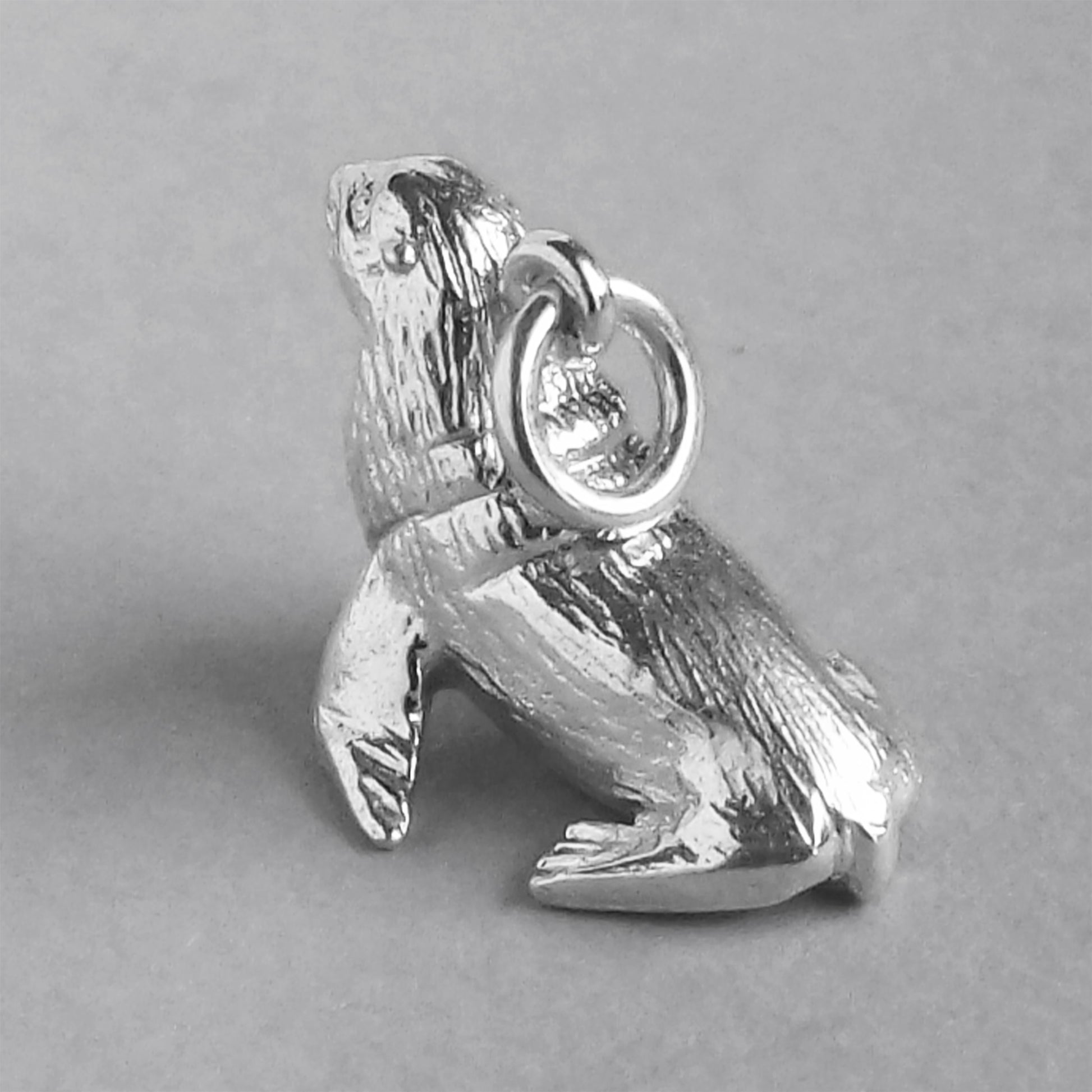 Sterling silver fur seal charm on a grey background