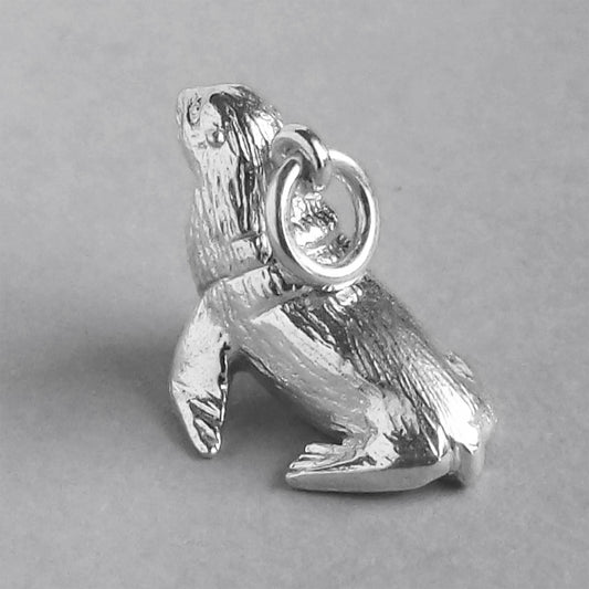 Sterling silver fur seal charm on a grey background