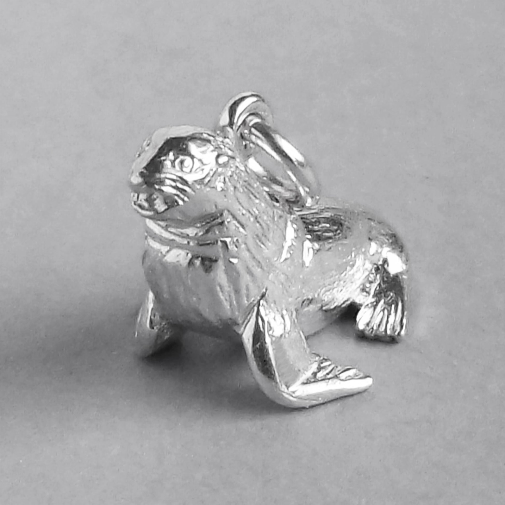 Sterling silver fur seal charm on a grey background