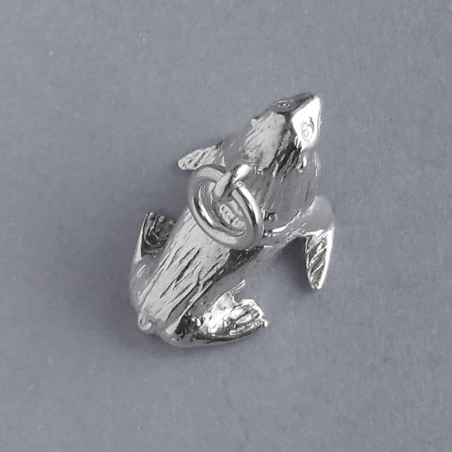 Sterling silver fur seal charm on a grey background