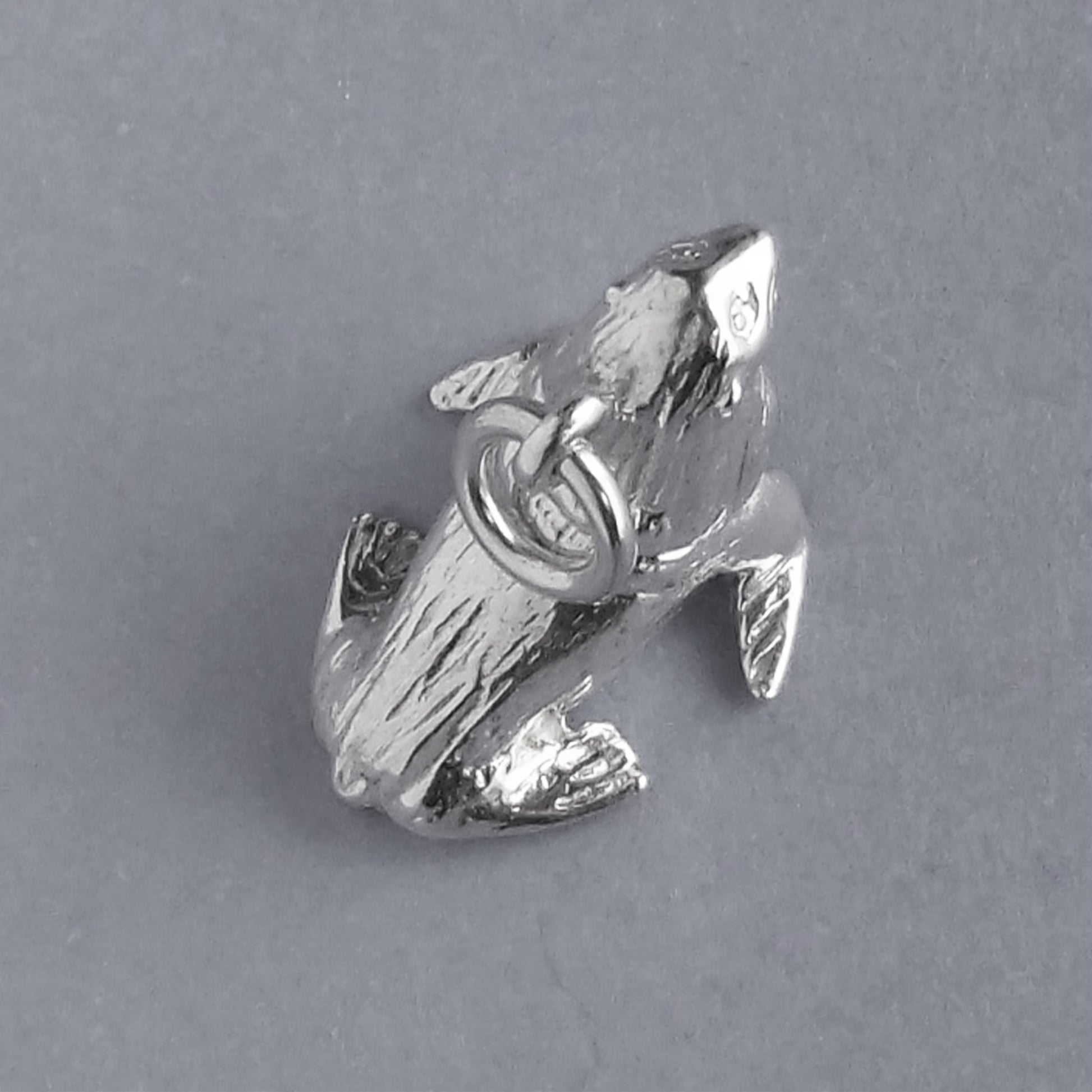 Sterling silver fur seal charm on a grey background
