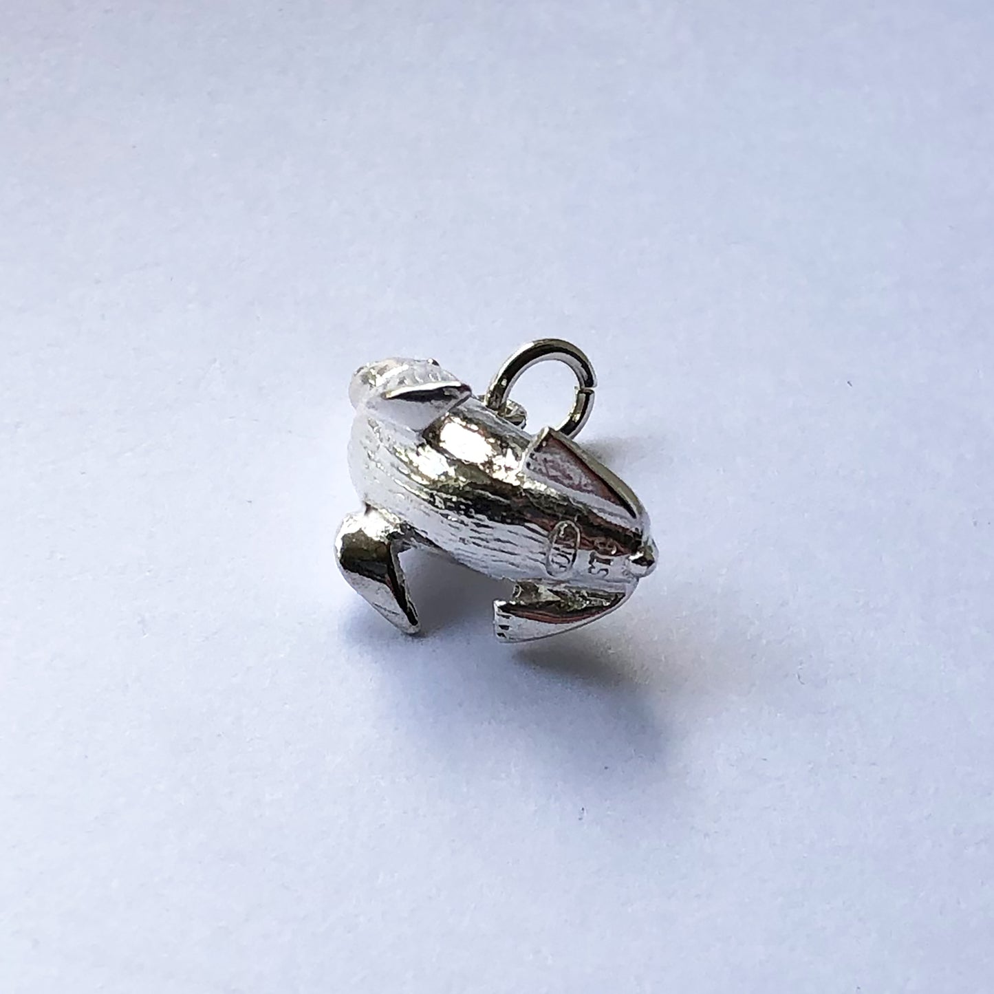 Underside view of sterling silver fur seal charm on a white background