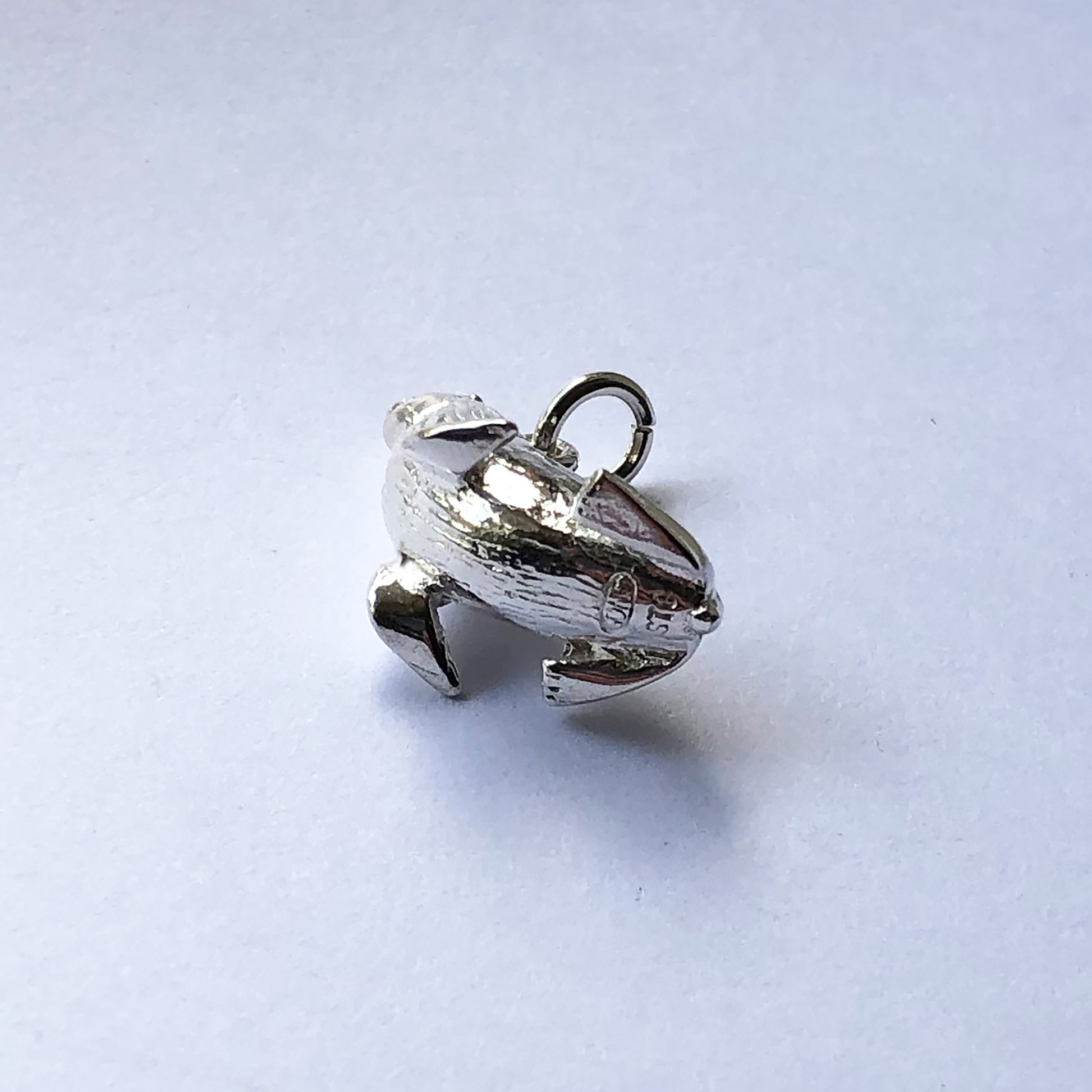Underside view of sterling silver fur seal charm on a white background