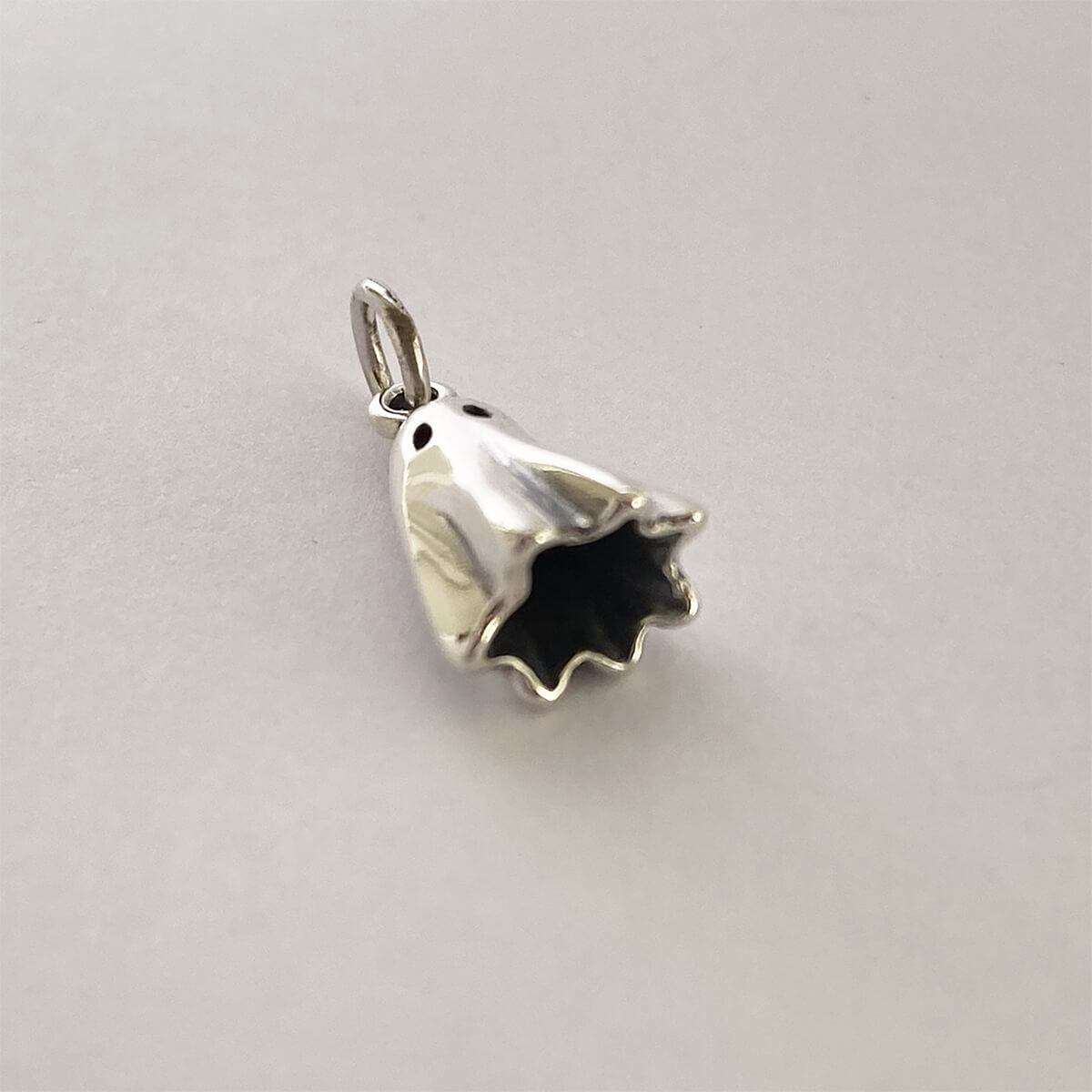 Sterling silver ghost charm on a grey background