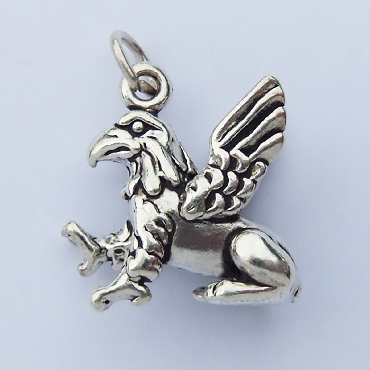 Sterling silver griffin charm on a light grey background