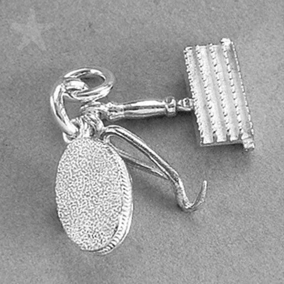 Sterling silver grooming kit charm on a grey background