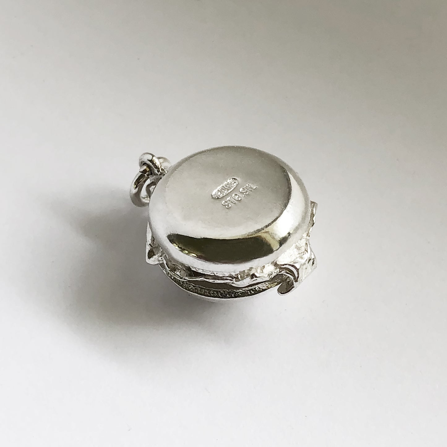 Underside of a sterling silver hamburger charm on a white background