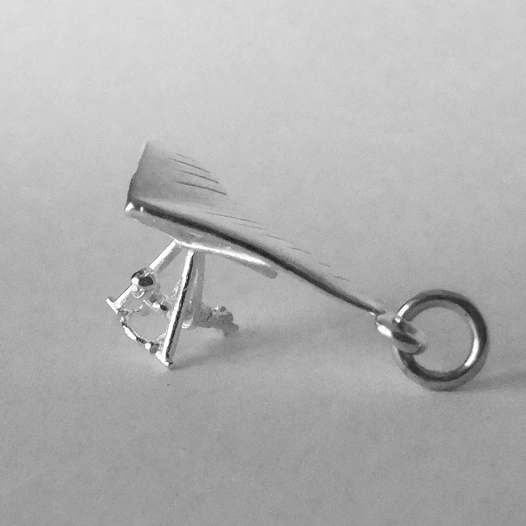 Sterling silver hang glider charm on a grey background