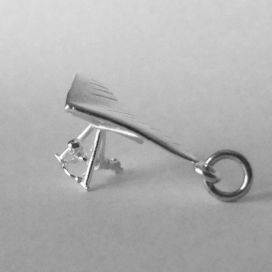 Sterling silver hang glider charm on a grey background