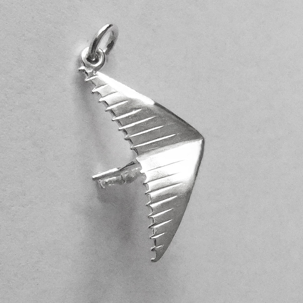Sterling silver hang glider charm on a grey background