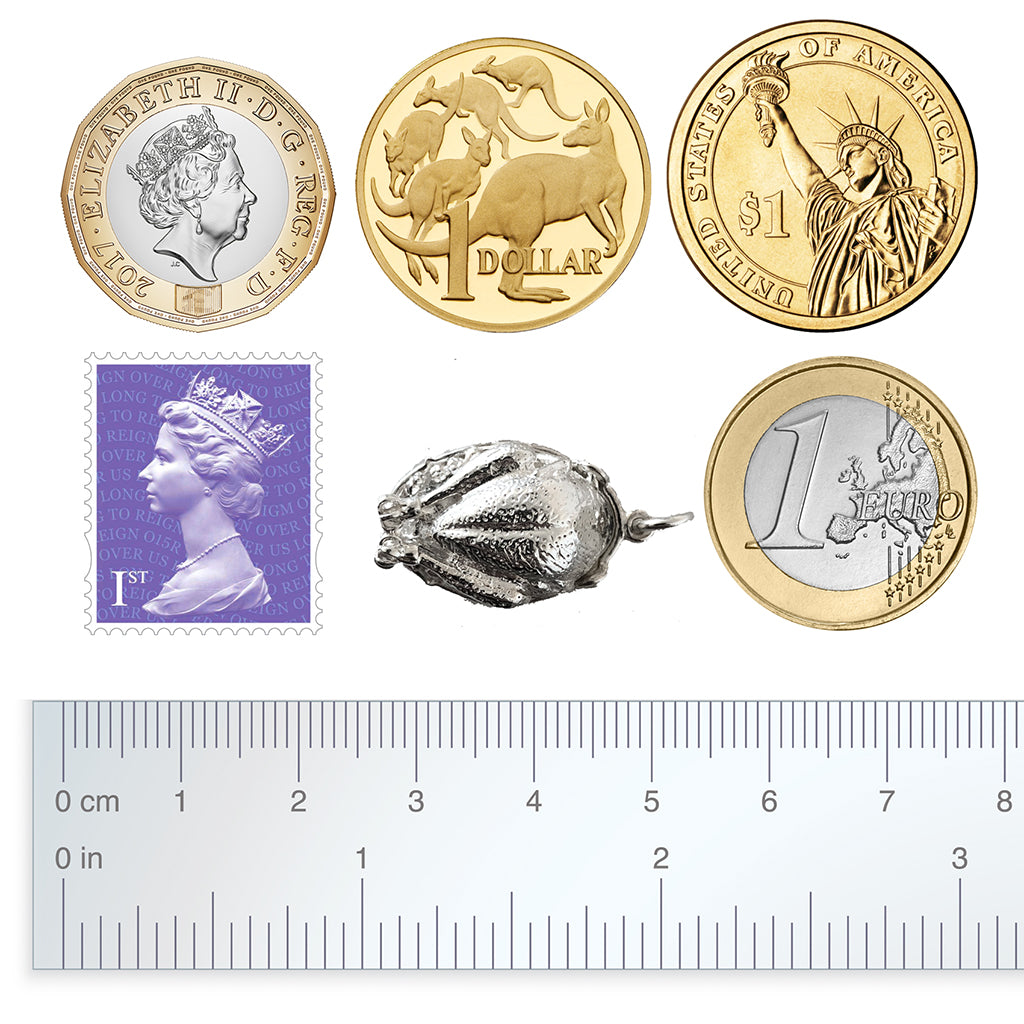 Sterling silver roast turkey charm with coins, postage stamp and ruler for scale on a white background