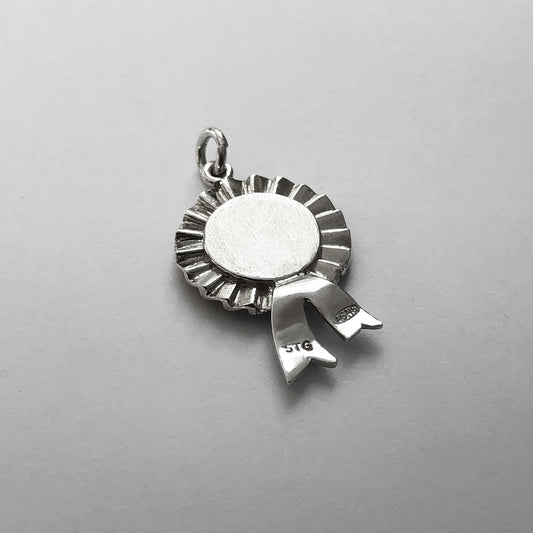 Back of a sterling silver first prize rosette charm on a grey background