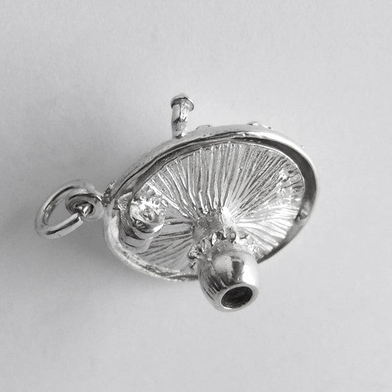Underside of a sterling silver toadstool charm on a white background