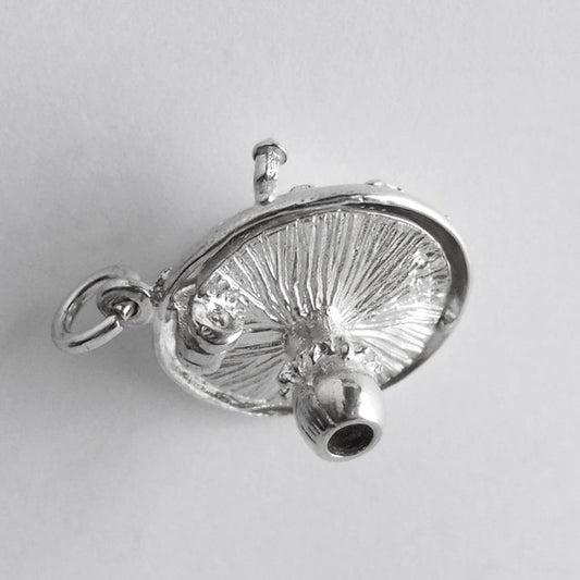 Underside of a sterling silver toadstool charm on a white background