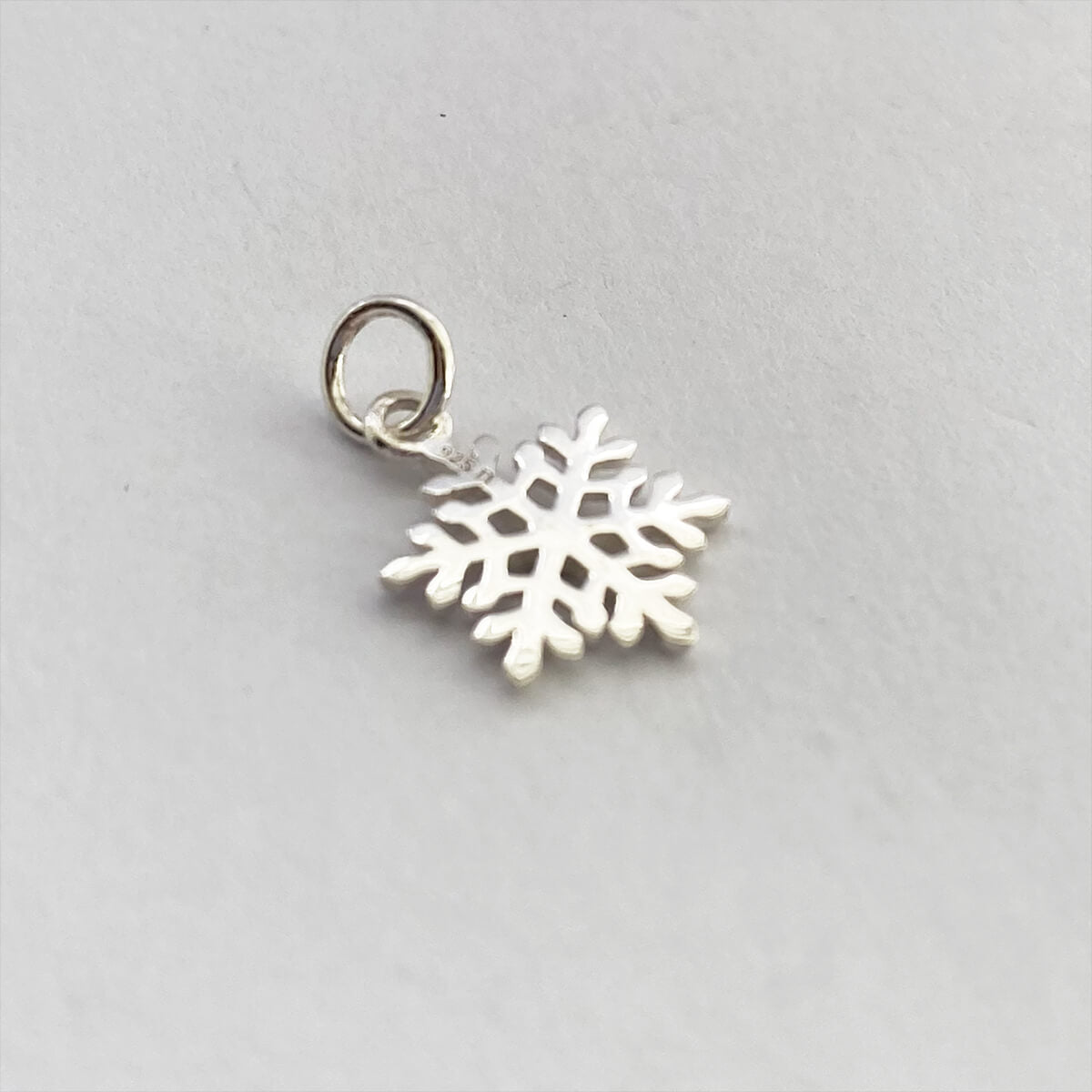 back of silver snowflake charm on a grey background
