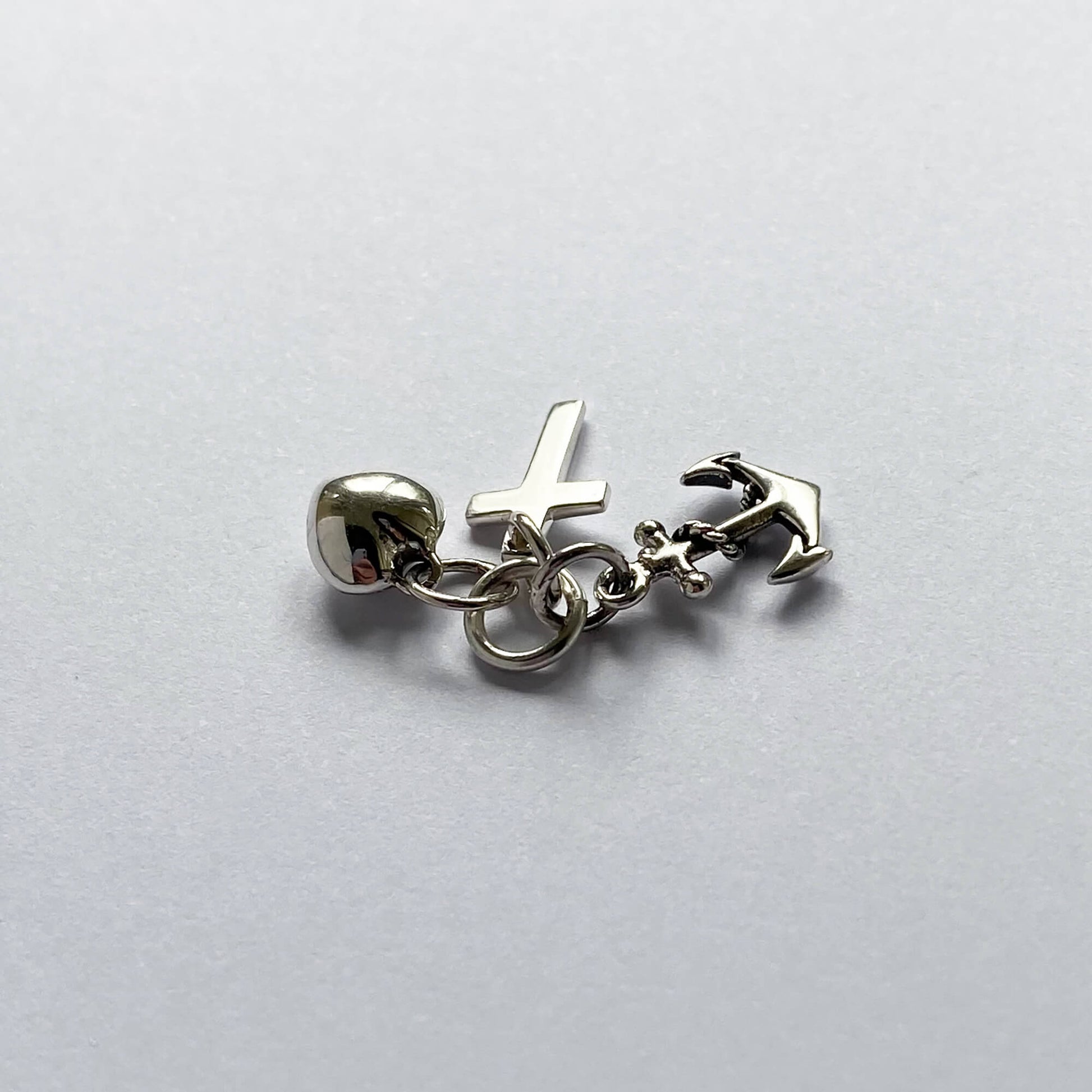 silver faith hope charity charm on grey background