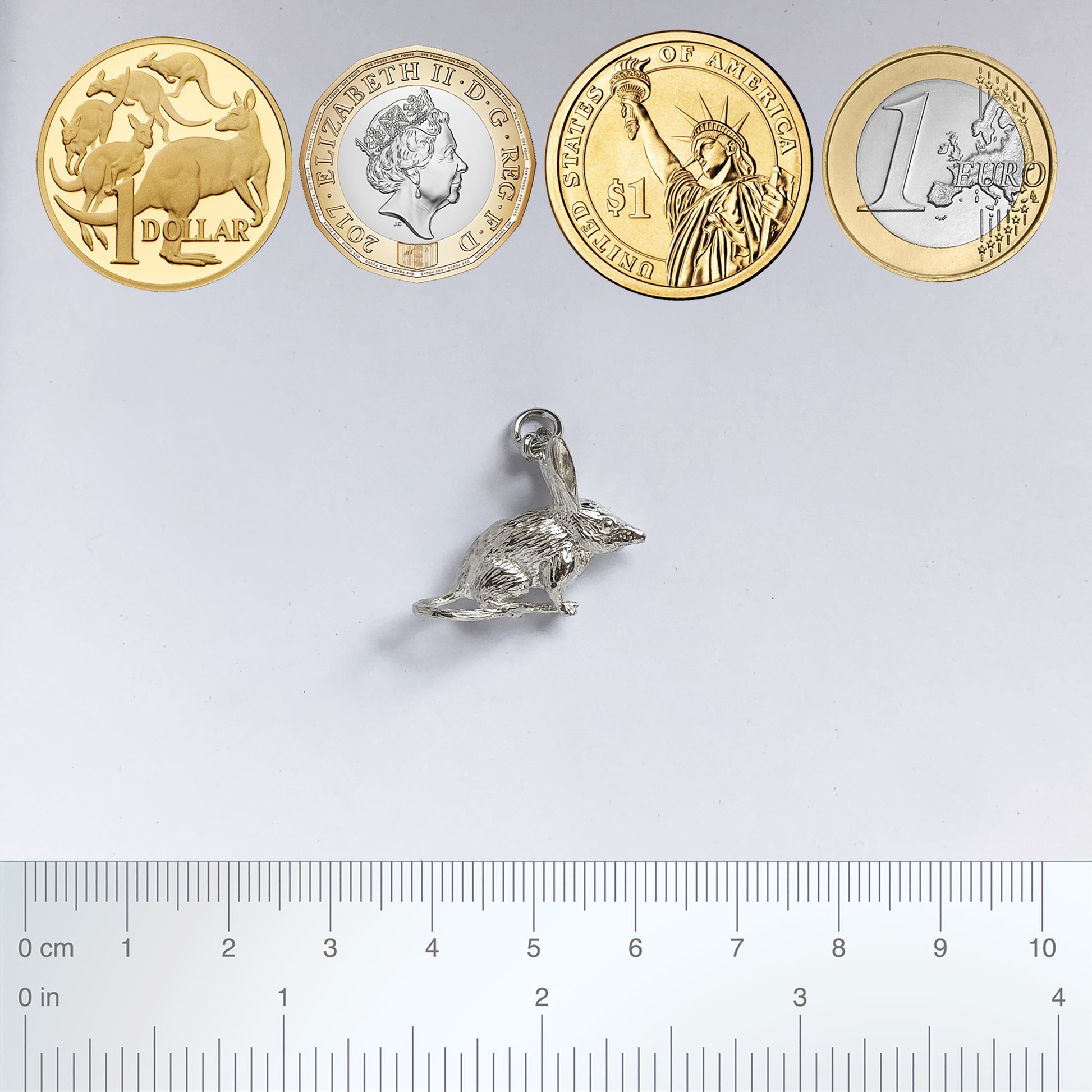 bilby charm in silver pictured with coins and ruler for scale