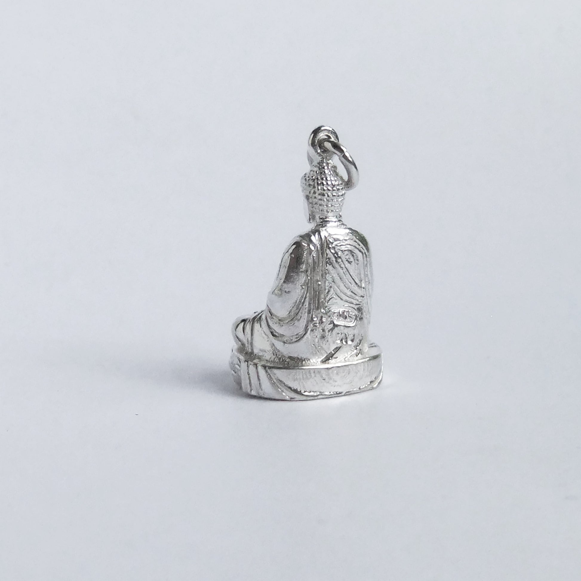 silver buddha charm from back on light grey background