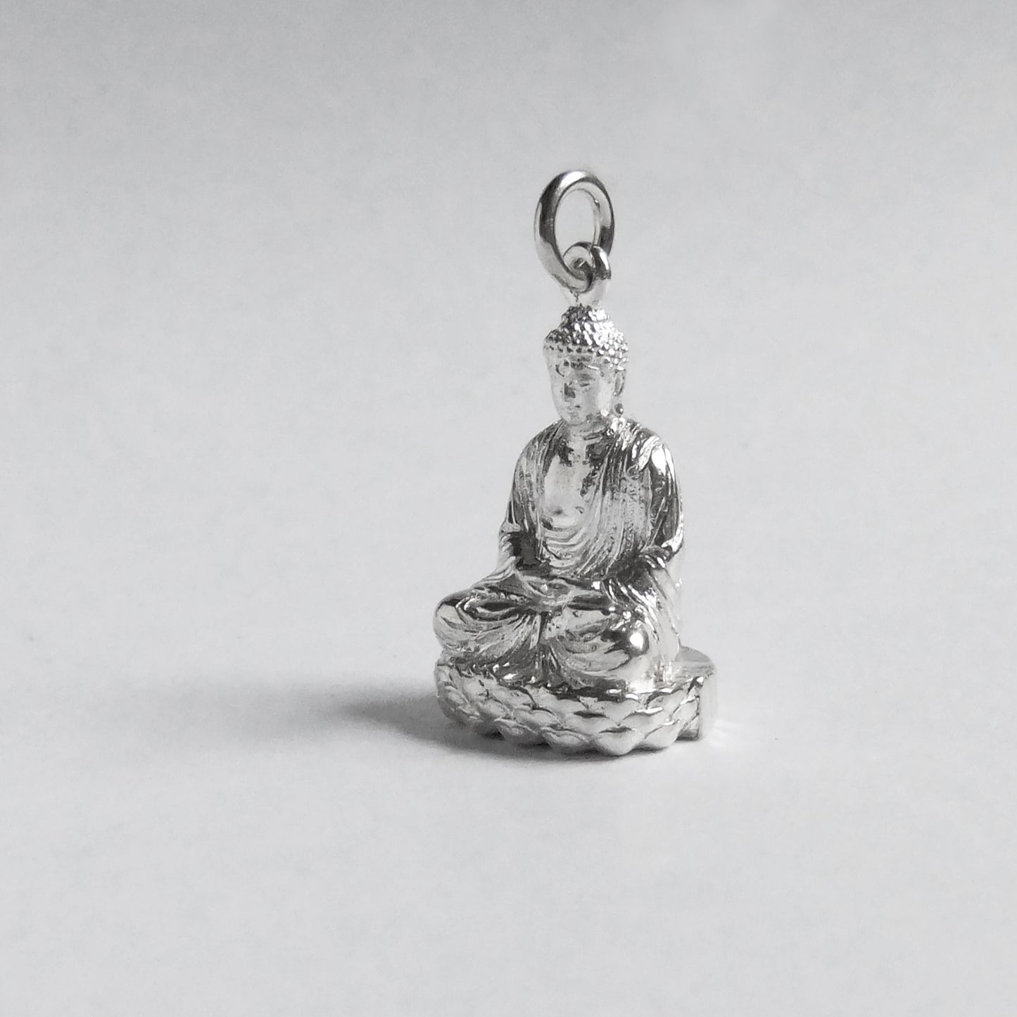 silver buddha charm on light grey background