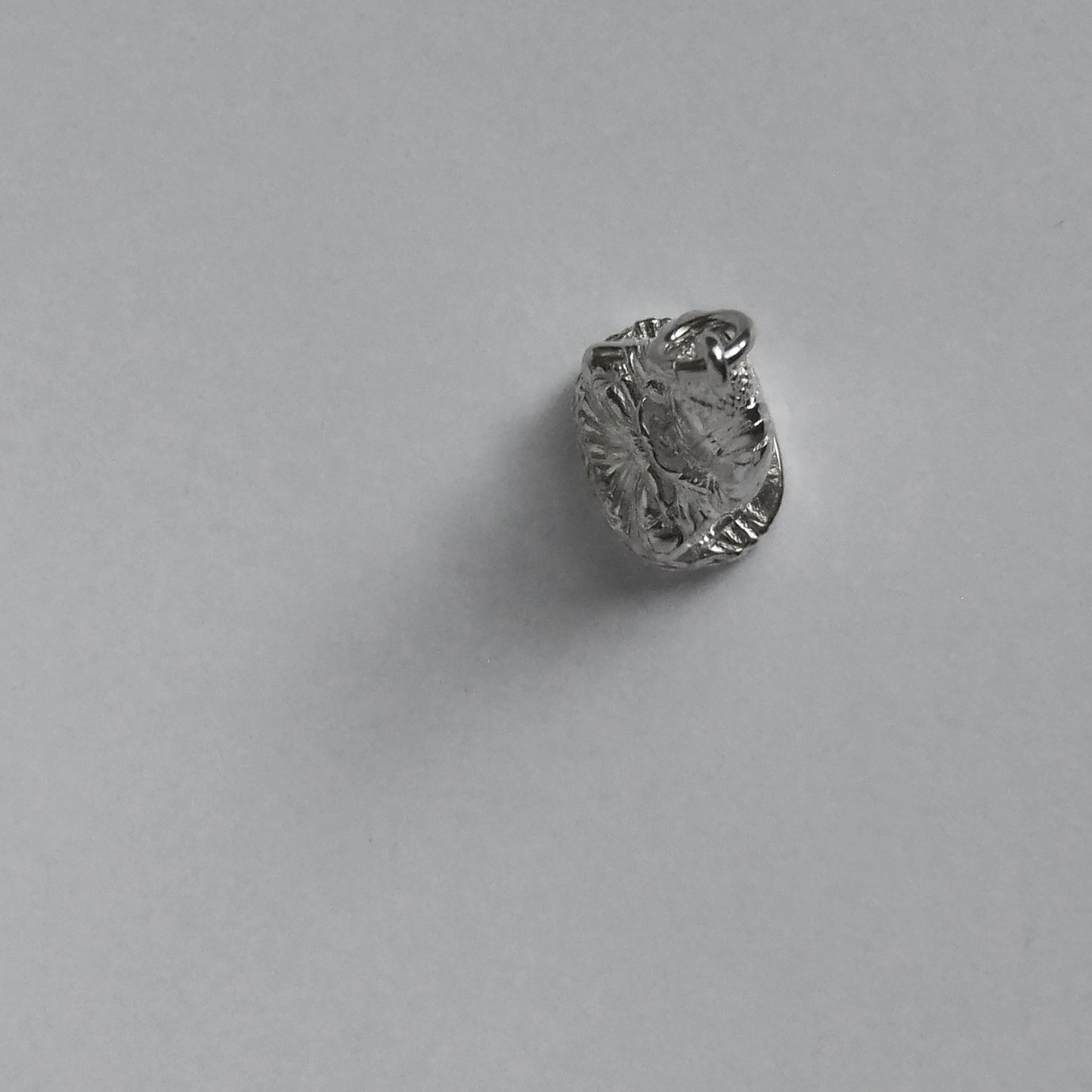 silver buddha charm pictured from above on a light grey background