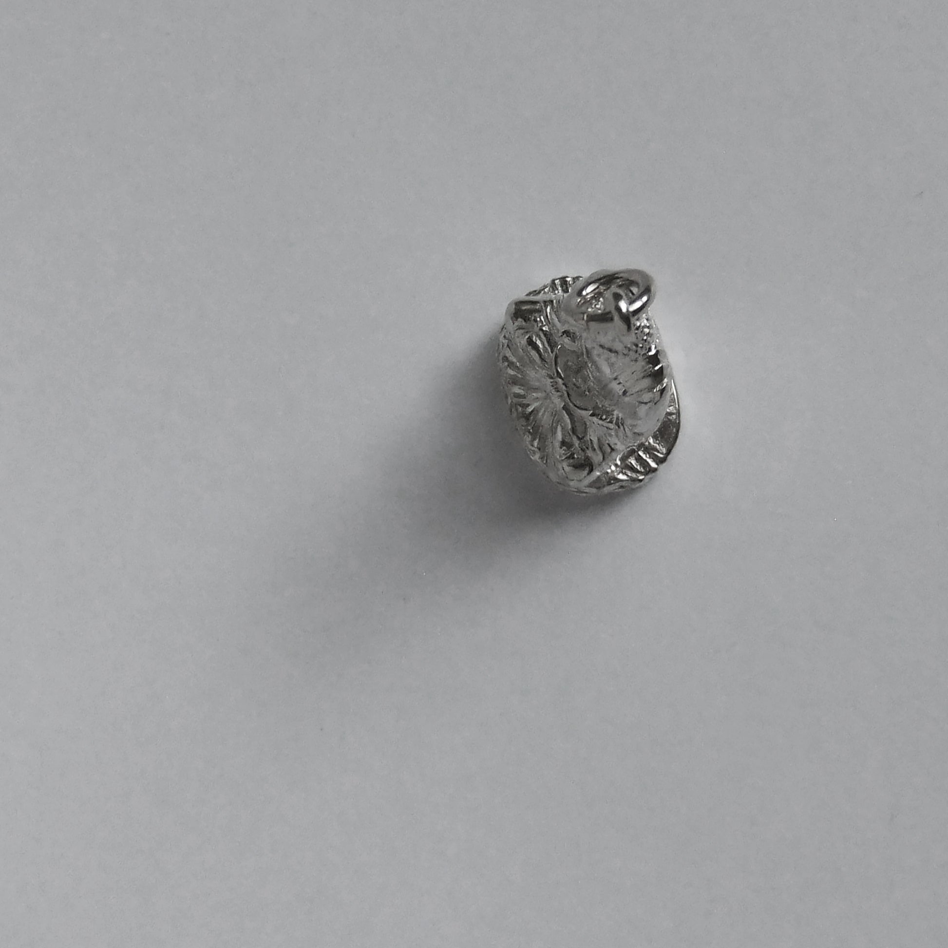 silver buddha charm pictured from above on a light grey background