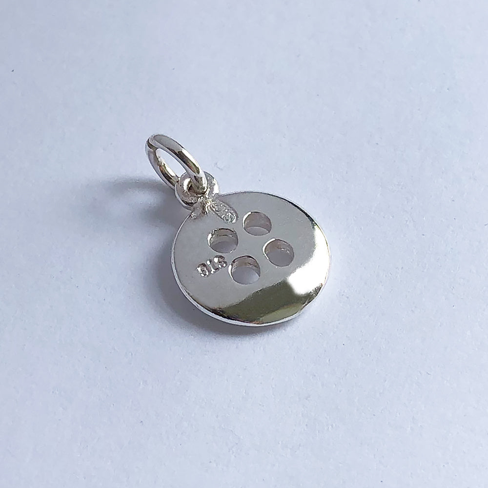 silver button charm on a light grey background