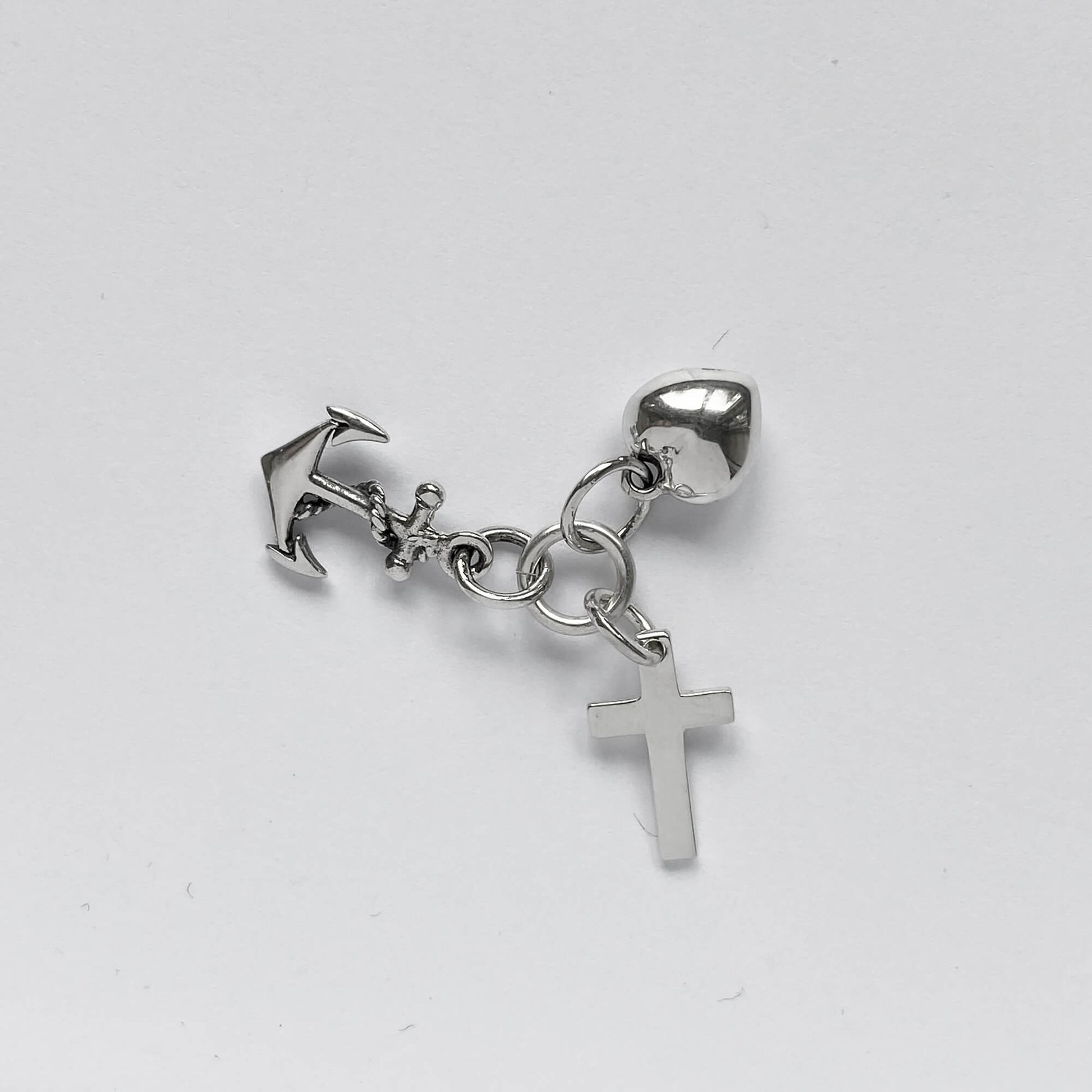 silver faith hope charity charm on light grey background