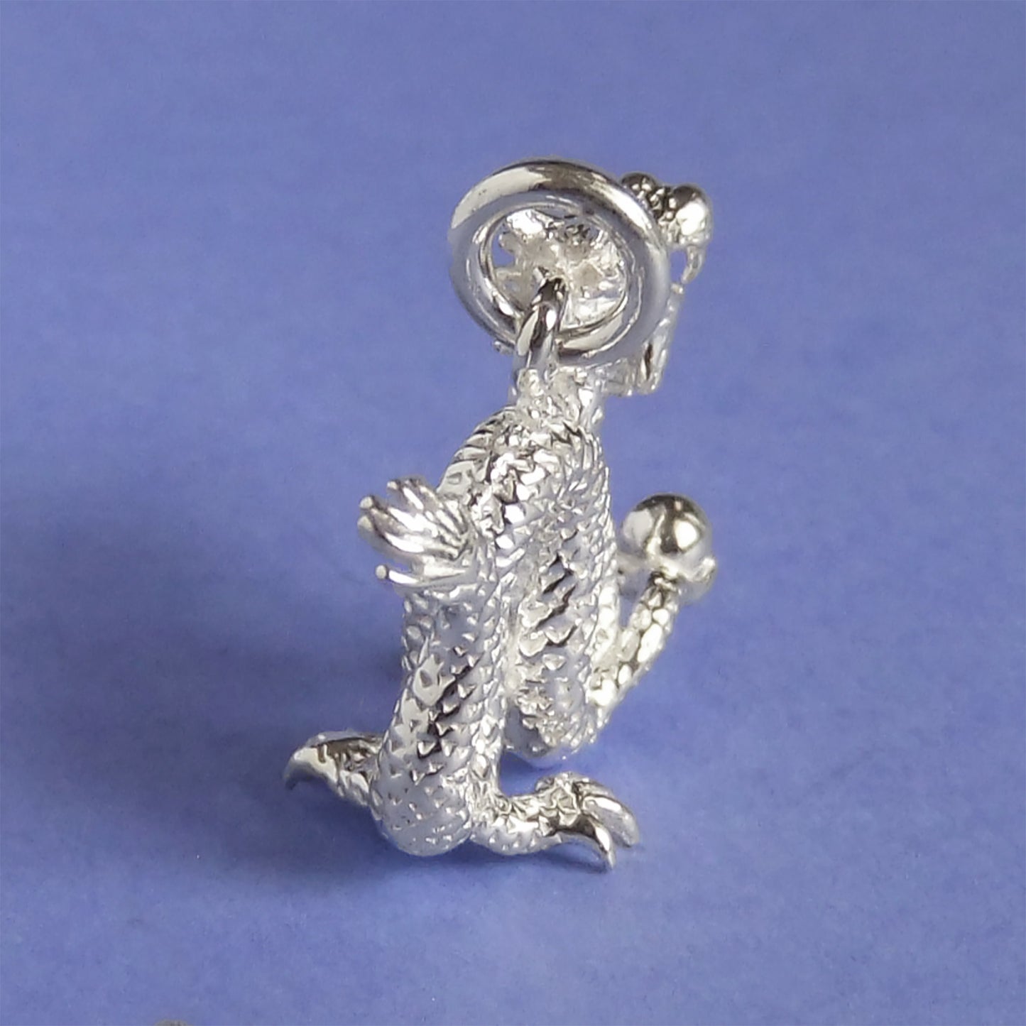 silver Chinese dragon charm on a purple background