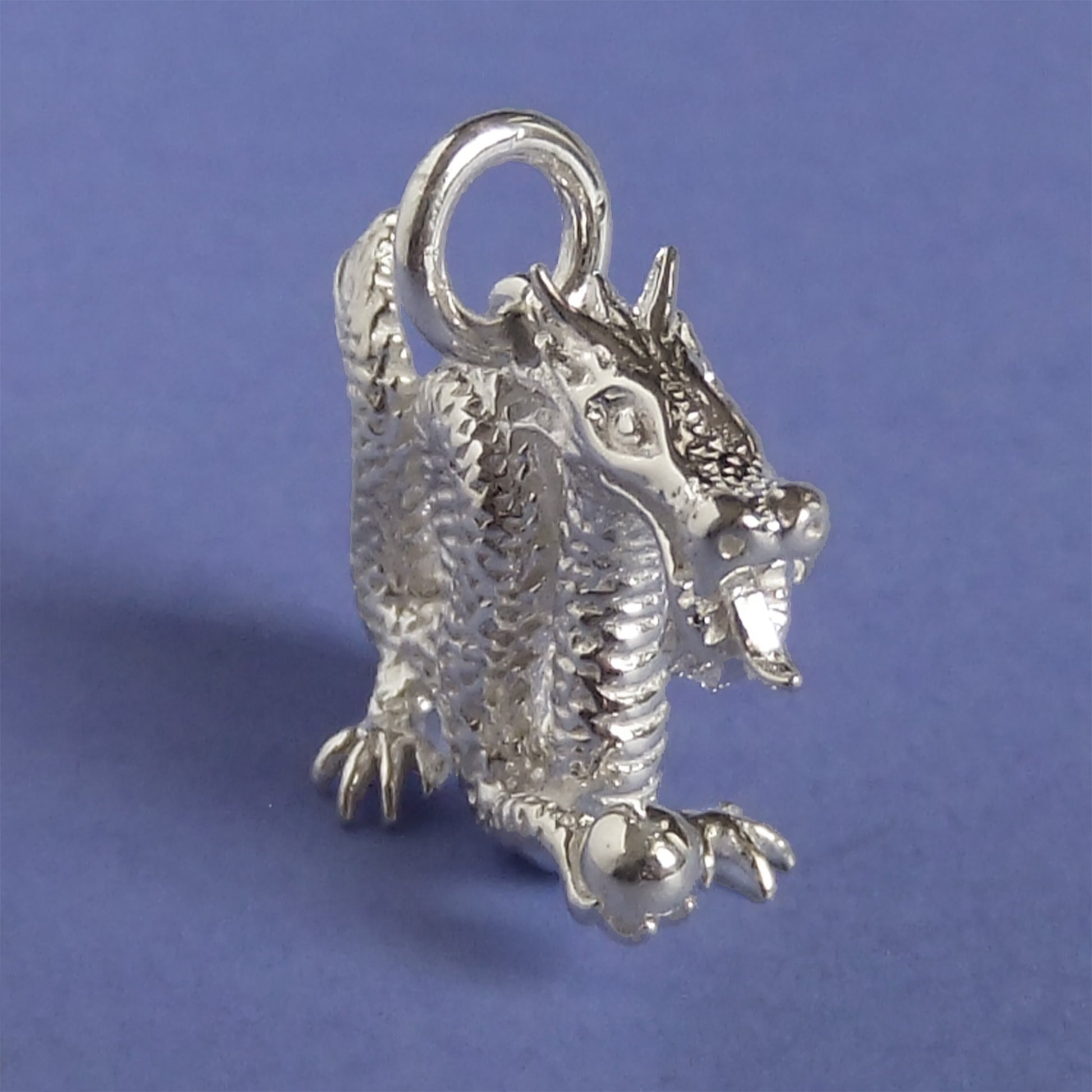 silver Chinese dragon charm on a purple background