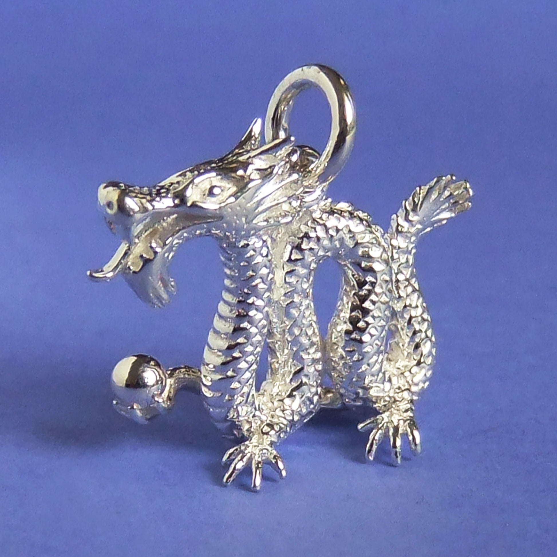 silver Chinese dragon charm on a purple background