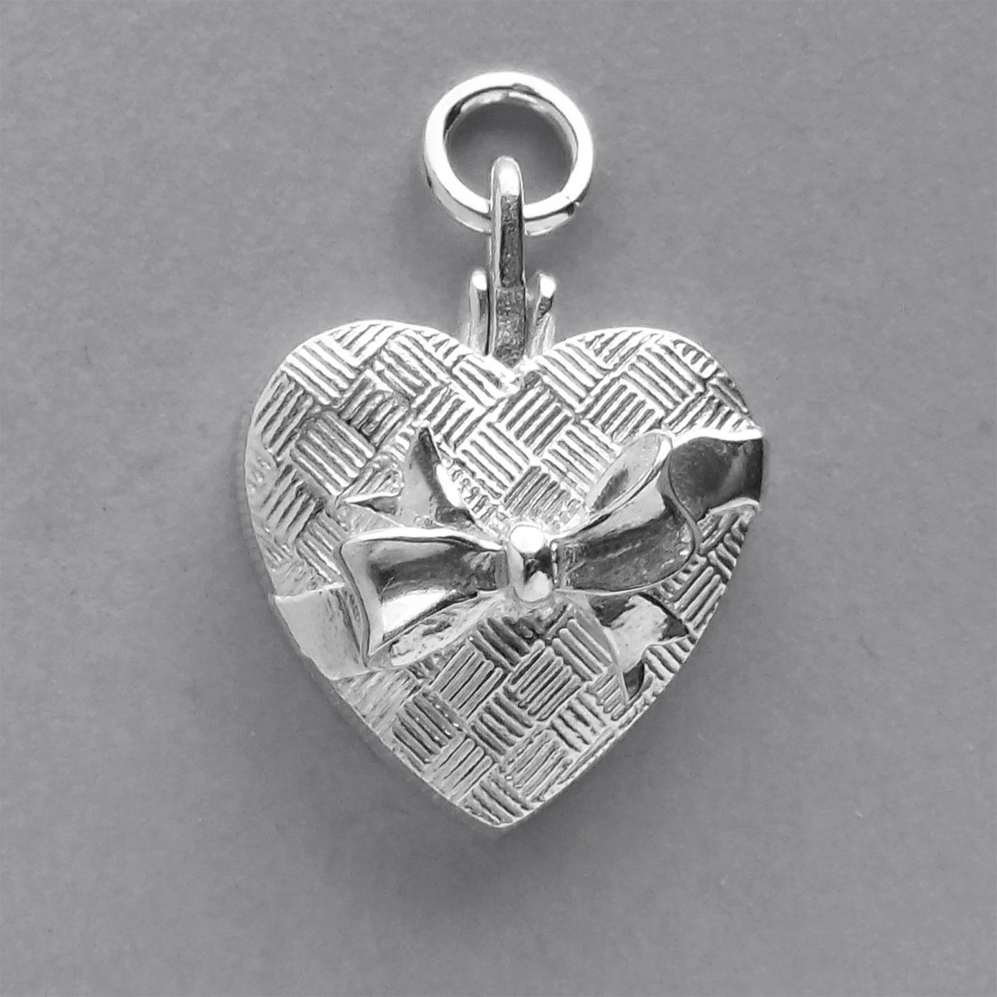 silver heart shaped chocolate box charm on a grey background