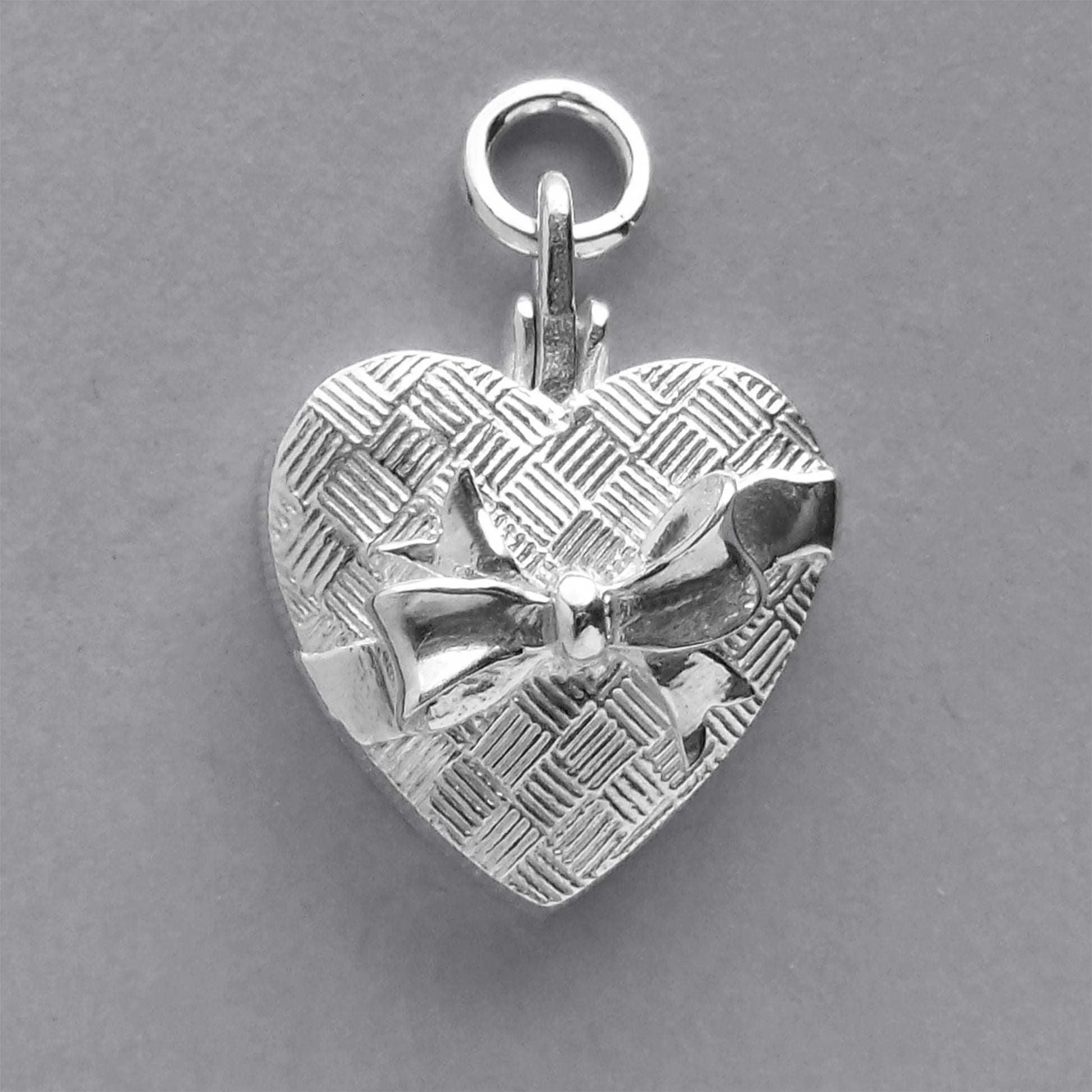 silver heart shaped chocolate box charm on a grey background