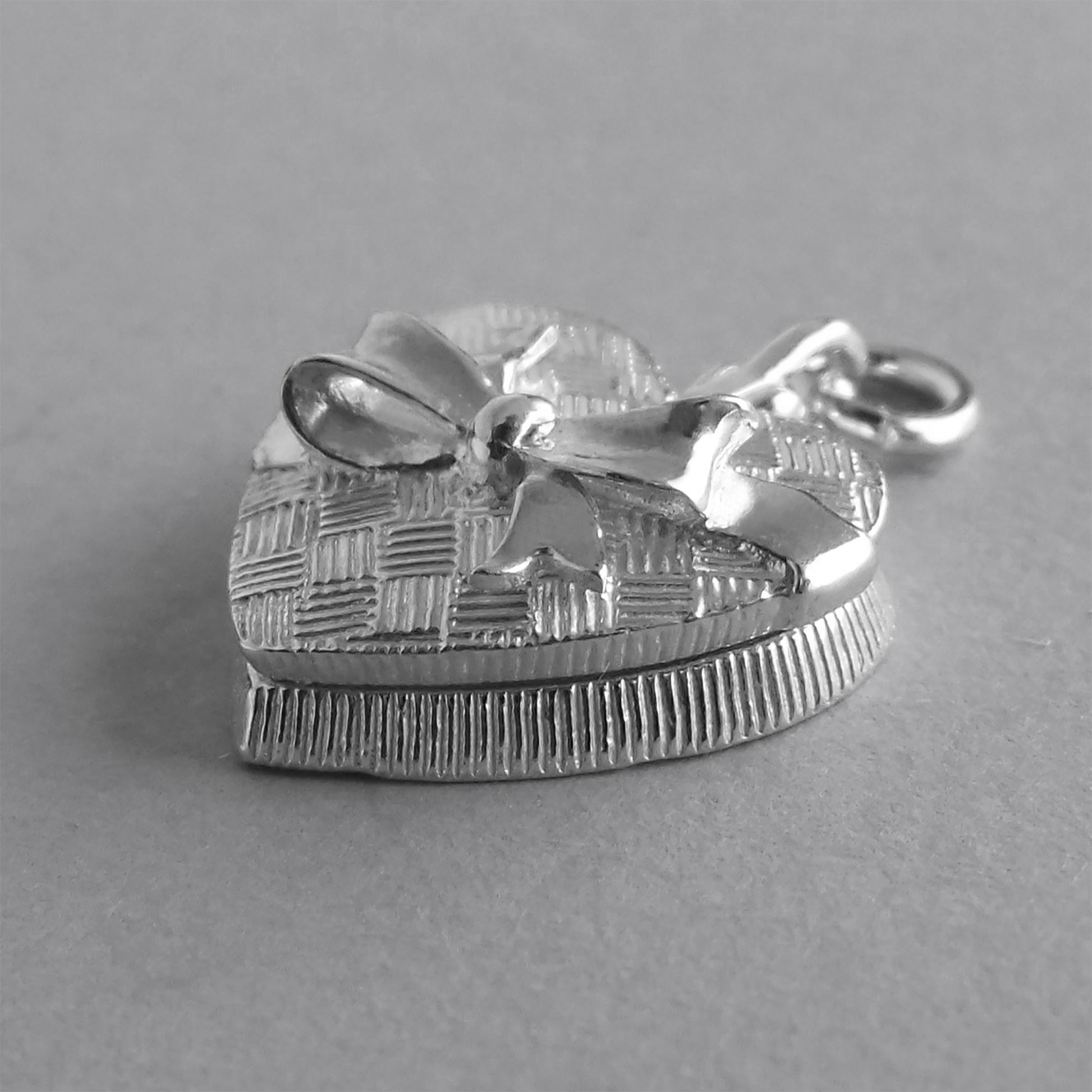 silver heart shaped chocolate box charm viewed from side on a grey background