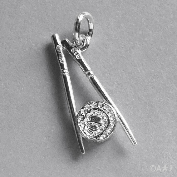 silver chopsticks and sushi charm on grey background