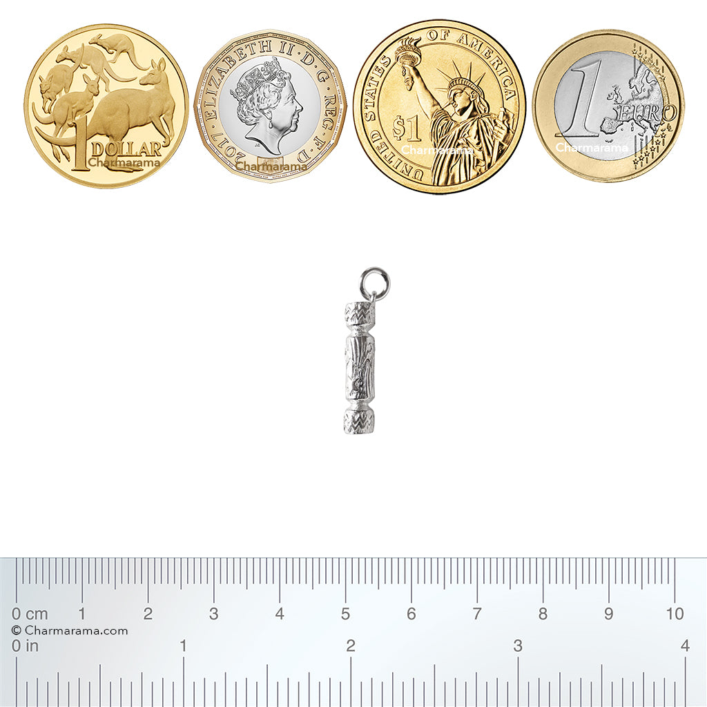 silver Christmas cracker charm with coins and ruler for scale on white background