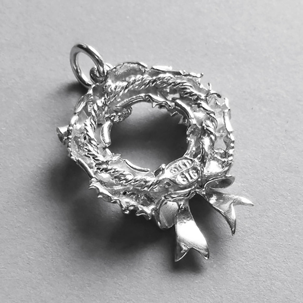silver Christmas wreath charm  seen from back on a light grey background