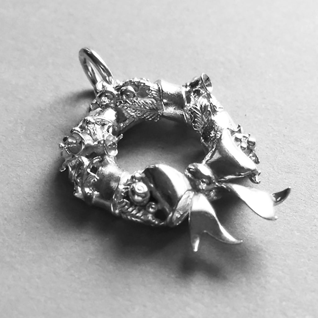 silver Christmas wreath charm on a light grey background