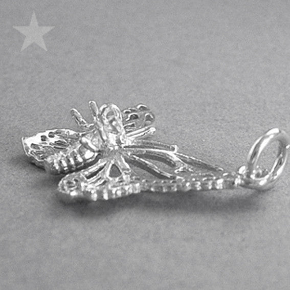 A silver filigree butterfly charm underside on a grey background.