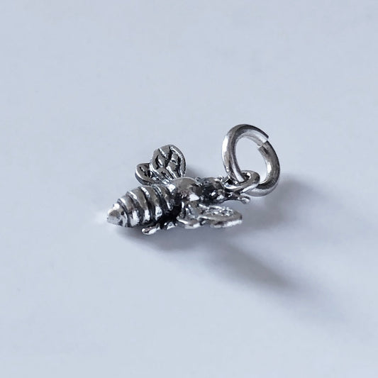 sterling silver tiny bee pendant on a light grey background