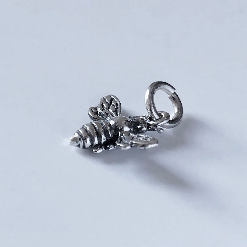 sterling silver tiny bee pendant on a light grey background