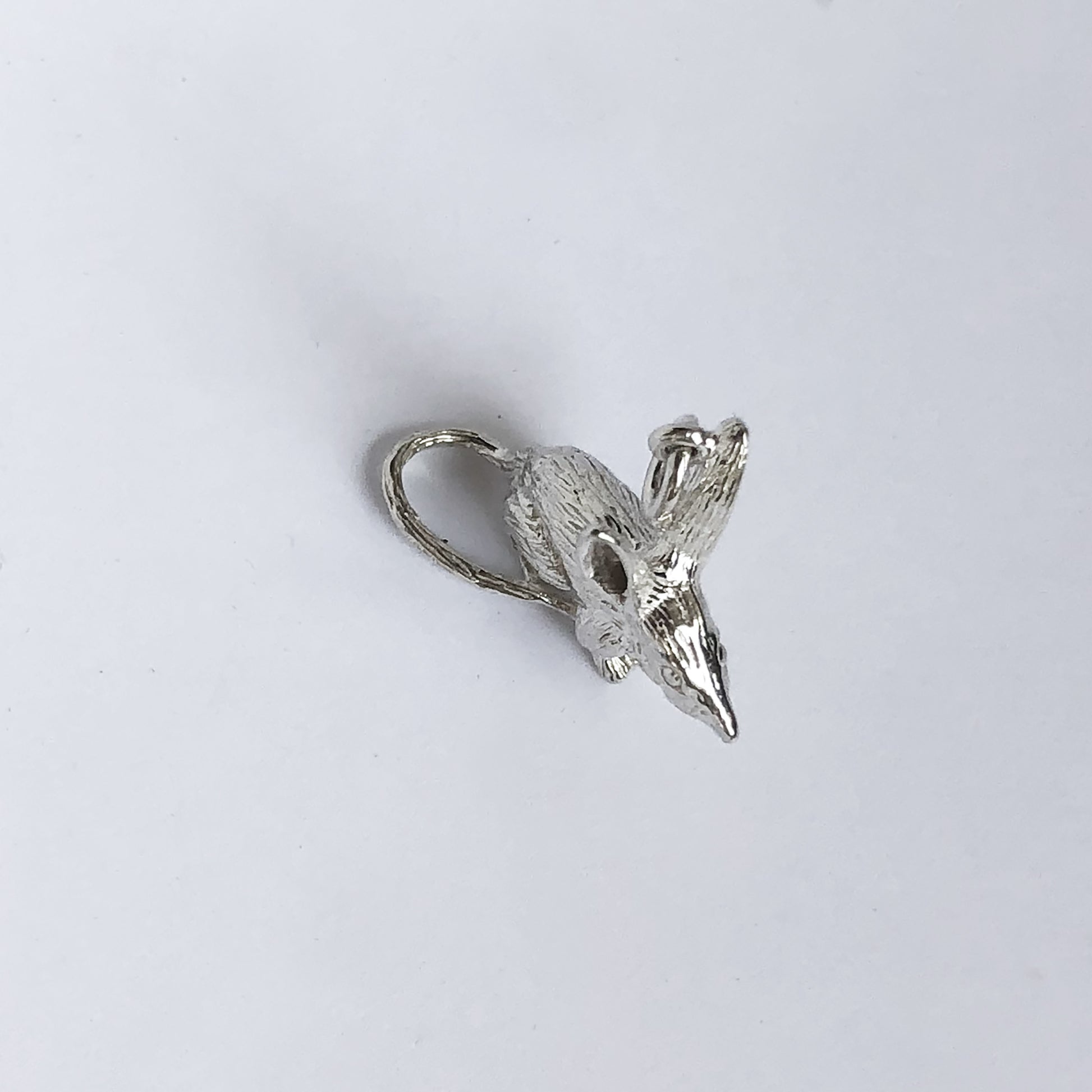 silver bilby charm seen from above, on a light grey background