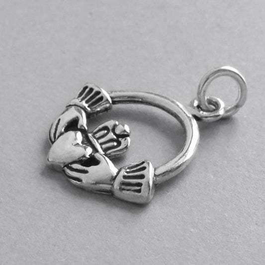 side view of silver Claddagh Irish crowned heart in hands symbol  on grey background
