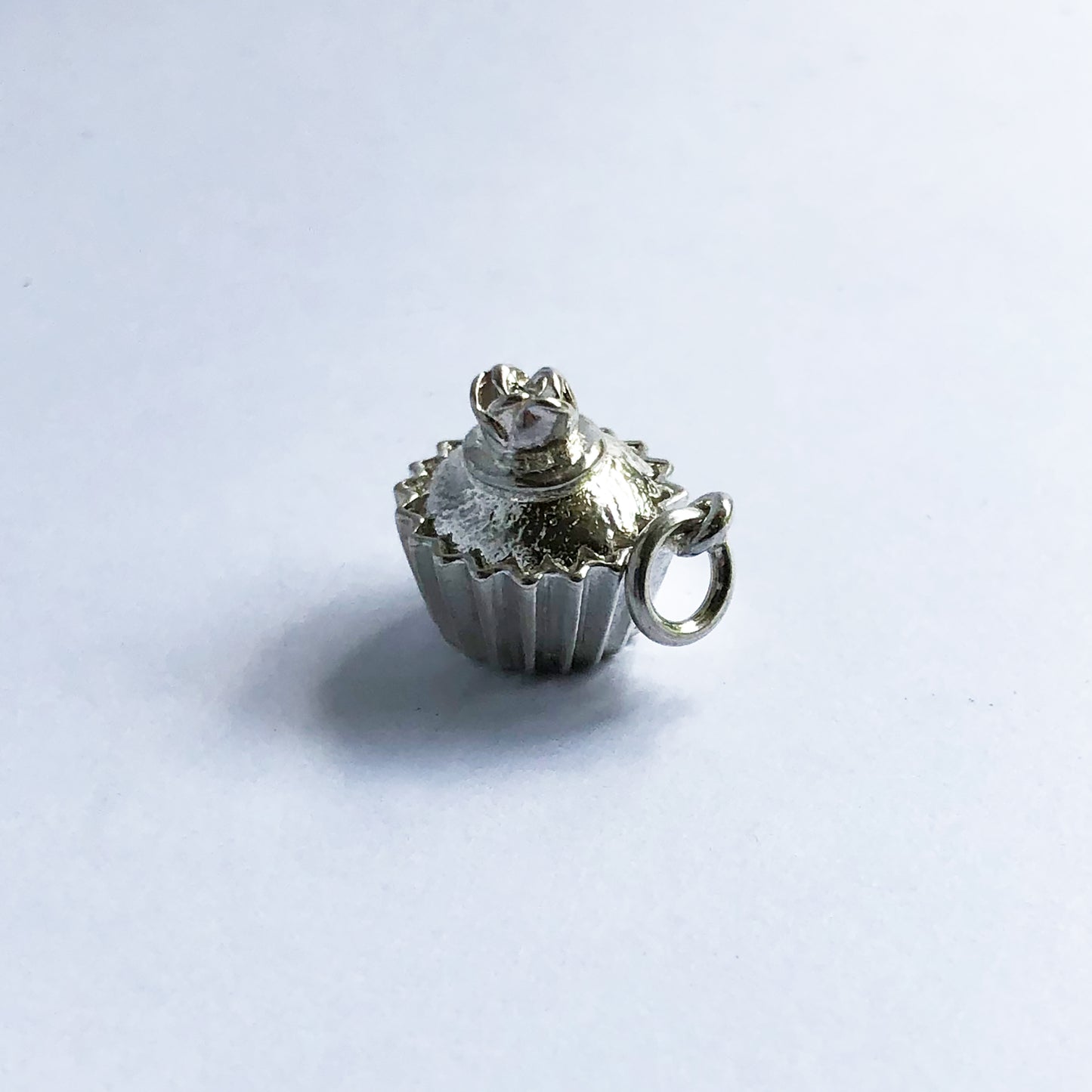 Sterling silver cupcake charm with rose decoration on a white background