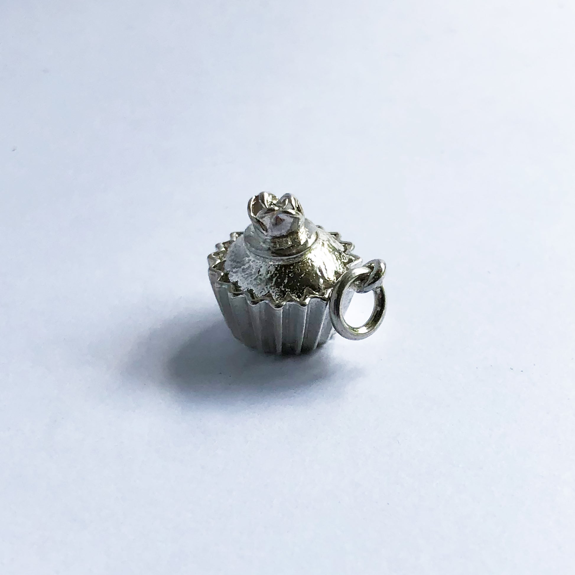 Sterling silver cupcake charm with rose decoration on a white background