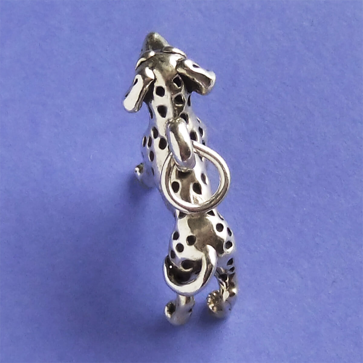 sterling silver Dalmatian dog charm viewed from above on a purple background