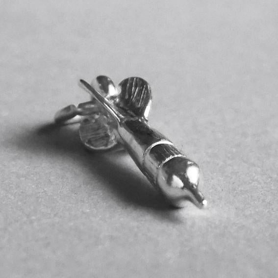 Sterling silver dart charm on a grey background