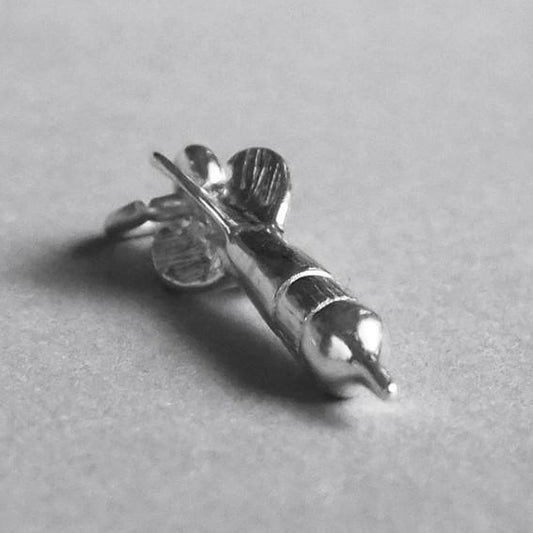 Sterling silver dart charm on a grey background