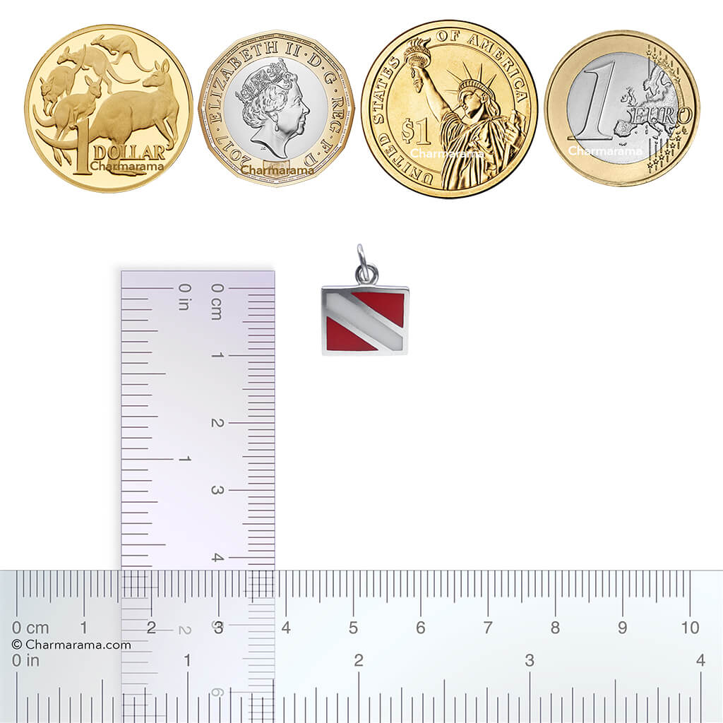 Sterling silver and enamel diving flag charm with coins and ruler for scale on a white background