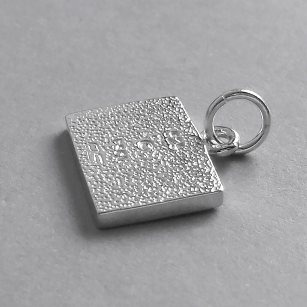 Sterling silver diving flag charm viewed from back on a grey background