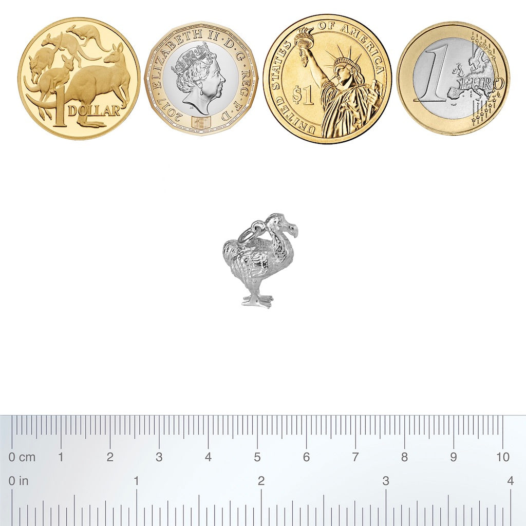 Sterling silver dodo charm with coins and ruler for scale on a white background